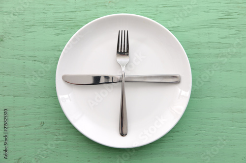緑の木製テーブルに置かれた白い皿とカトラリーによる次の料理を待機の合図