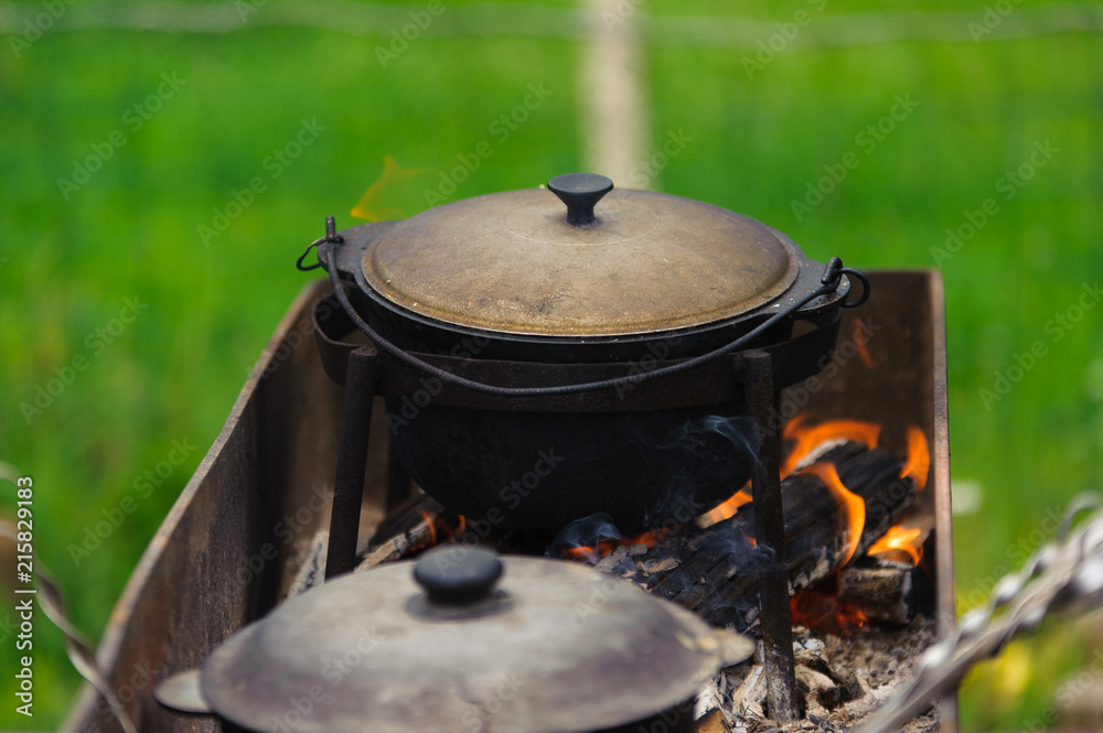 Cooking in a huge cast-iron pot. street food. picnic Cooking in a huge cast-iron pot. street food. picnic