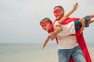 Father and son playing superhero on the beach at the day time.
