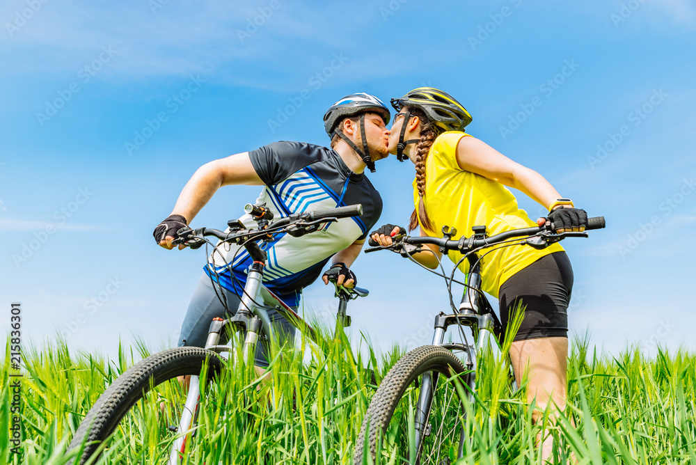 young kissing strong man and woman standing at green field with young kissing strong man and woman standing at green field with