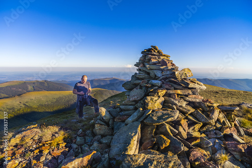 Tourist photographing a pile of rocks on top of the mountain