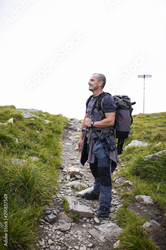 Photographer with backpack and camera hiking on a mountain trail