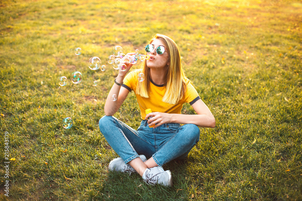 Fototapeta premium Young woman are blowing soap bubbles outdoors