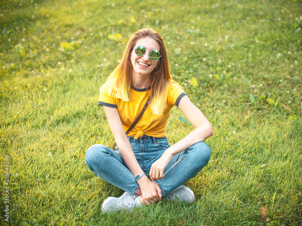 Fototapeta premium Woman sitting on the grass in the park