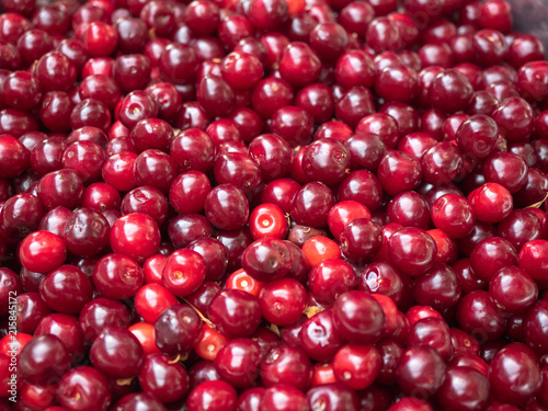 Background of red ripe cherry. Close up view on red berries. Texture of ripe cherry piled on the ground. Blurred background. Soft selective focus