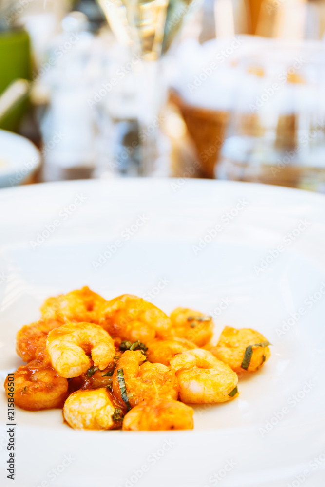 Shrimps in tomato sause at the table. Outdoor Italian restaurant terrace. Concept of summer authentic meal Shrimps in tomato sause at the table. Outdoor Italian restaurant terrace. Concept of summer authentic meal