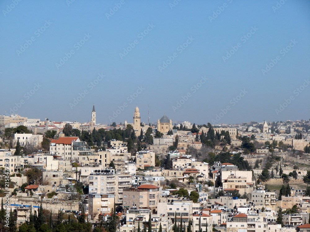 Panorama of the streets, buildings and temples of the city of Jerusalem from the height of the bird's eye on the background of a clean blue sky.