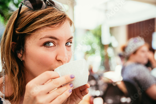 Junge Frau trinkt Kaffee und blickt in die Kamera  Italien