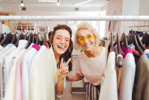 Shopping together. Two beautiful beaming women smiling broadly having fun while shopping together