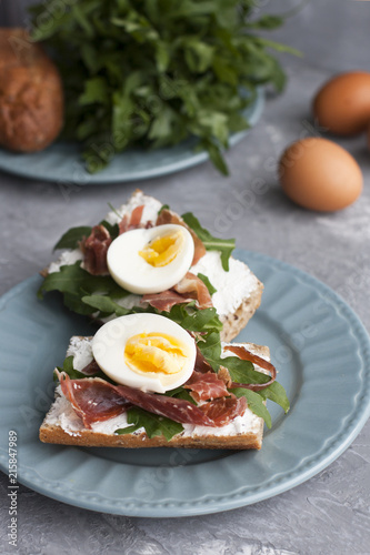 Sandwiches with whole grain bread, homemade cheese, arugula, ham and egg. Healthy snack.