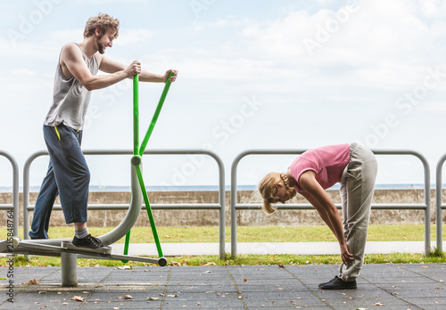 Man exercising on elliptical trainer and woman.