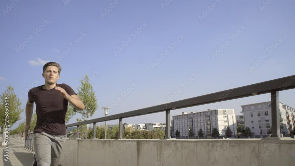 Portrait shot of a freerunner entering the frame and running along a narrow concrete bridge. Portrait shot of a freerunner entering the frame and running along a narrow concrete bridge.