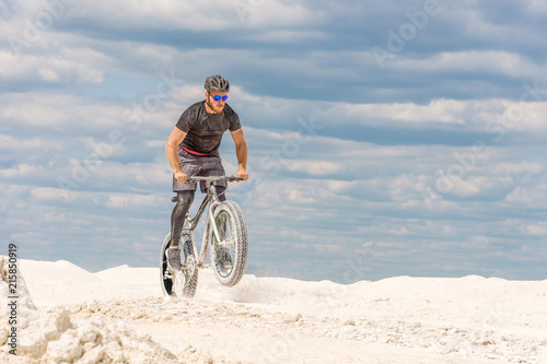 Training a bicyclist in a chalky quarry. A brutal man on a fat bike. © Mikhail