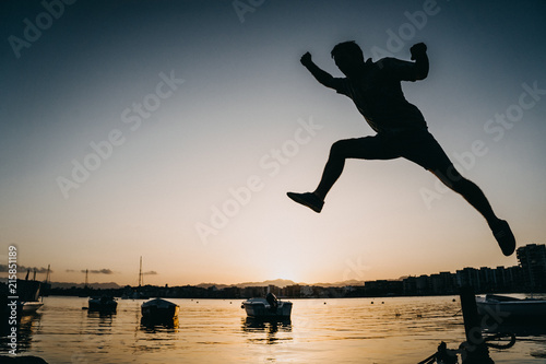 .Young people with funny and relaxed attitude  playing and jumping at the seashore on a beautiful summer sunset. Lifestyle.