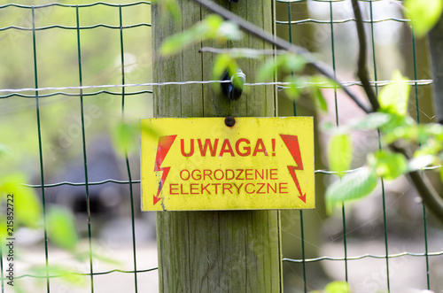 Warning sign with a live fence in polish language (uwaga ogrodzenie elektryczne pod napieciem).