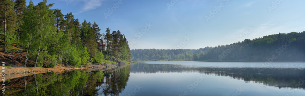 Panorama of mirror lake with a lonely house on the shore