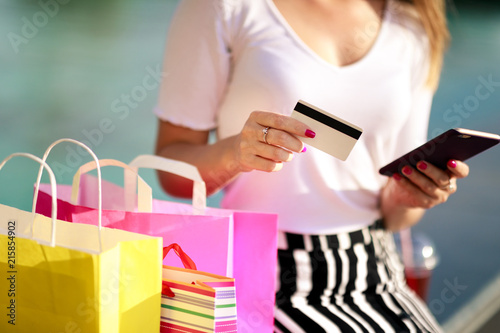 Cheerful girl with a phone, a bank card and shopping at the mall. Quickly and easily make an order online, pay, get a profitable offer