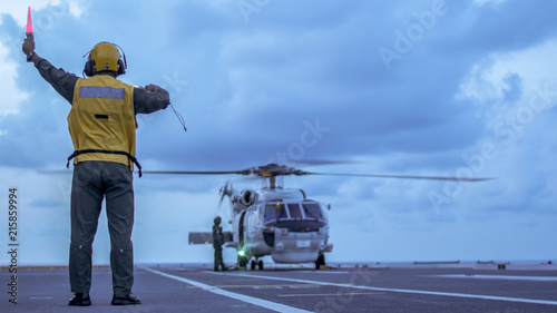 Signal man give a signal to anti-submarine warfare helicopter on the aviation deck of aircraft carrier.