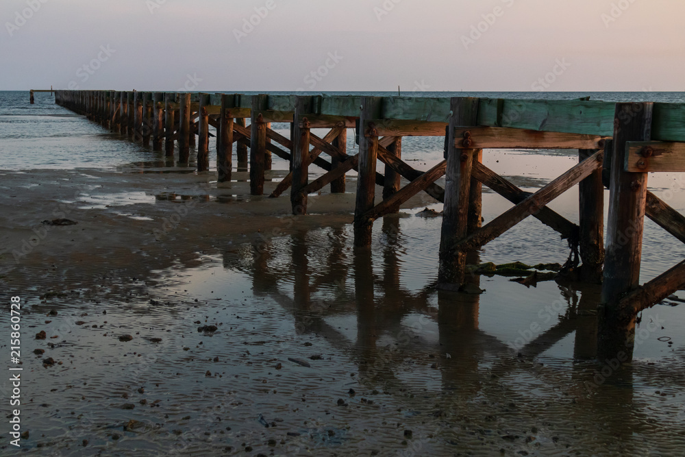 Old wooden pier and  ocean in background at sunset