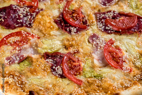 Pizza with tomato, ham, cheese on a wooden table