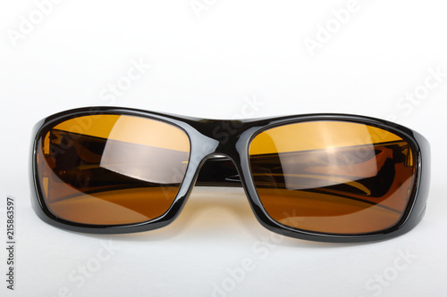 Sunglasses with black plastic frame and yellow glass on a white background