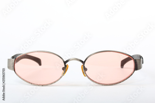 Old scratched sunglasses with metal frame and pink glass on a white background