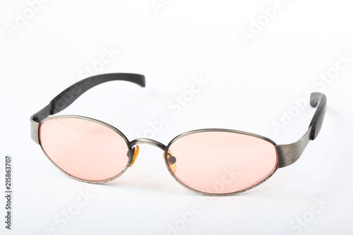 Old scratched sunglasses with metal frame and pink glass on a white background