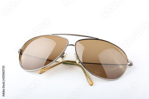 Scratched old classic sunglasses with metal frame and brown lenses on a white background