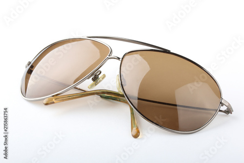 Single scratched old classic sunglasses with metal frame and brown lenses on a white background