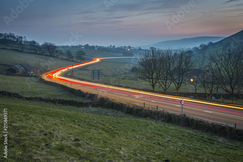 View of vehicle trail lights on A623 at Sparrowpit at dusk, Peak District National Park, Derbyshire photo