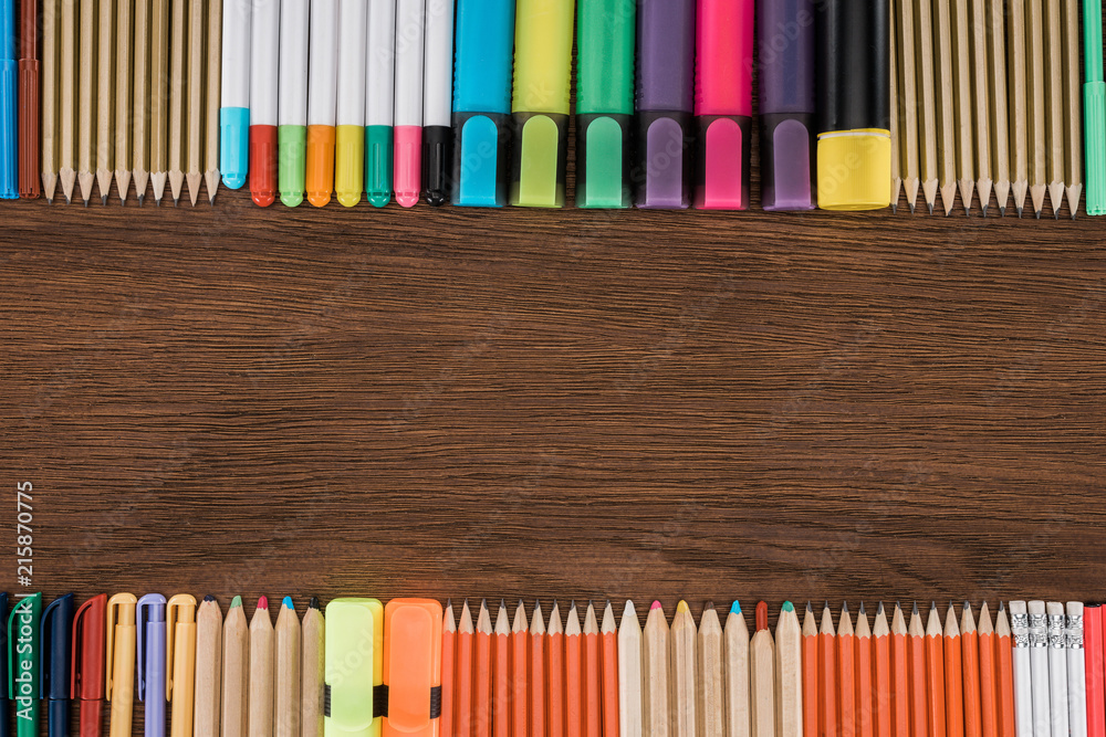 Obraz premium elevated view of arranged colorful pencils and markers on wooden table