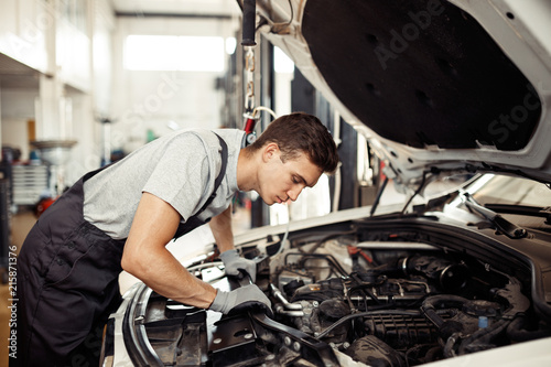 Safety sirst: a good-looking car mechanic is checking the engine