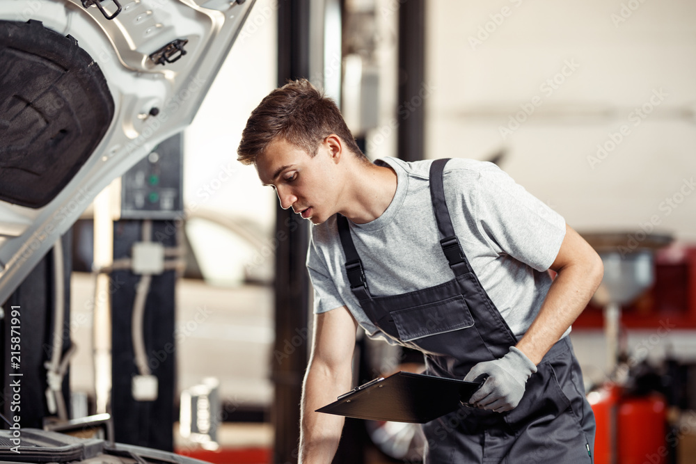 A young automechanic is checking the results of his work at a car service A young automechanic is checking the results of his work at a car service