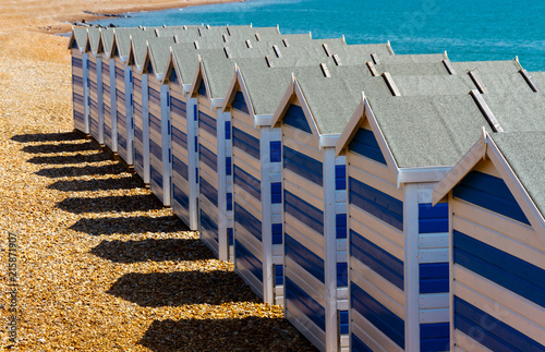 Fototapeta Naklejka Na Ścianę i Meble -  A line of blue beach huts on a pebble beach