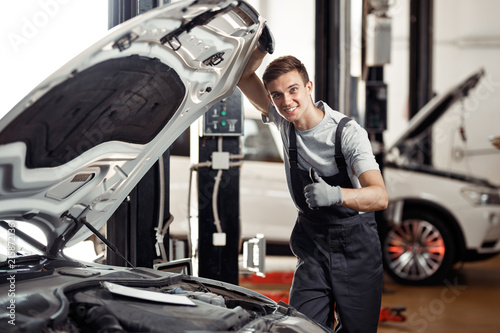 An attractive young car mechanic is smiling: car service and mai