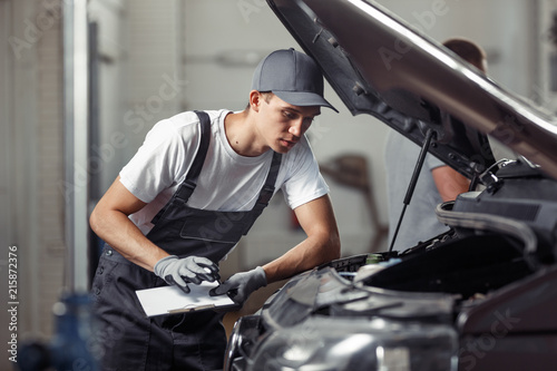 A mechanic is fixing a car at a car service © Leika production