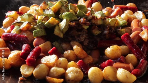 salting roasted potato, sausage and zucchini  in baking tray on open fire 