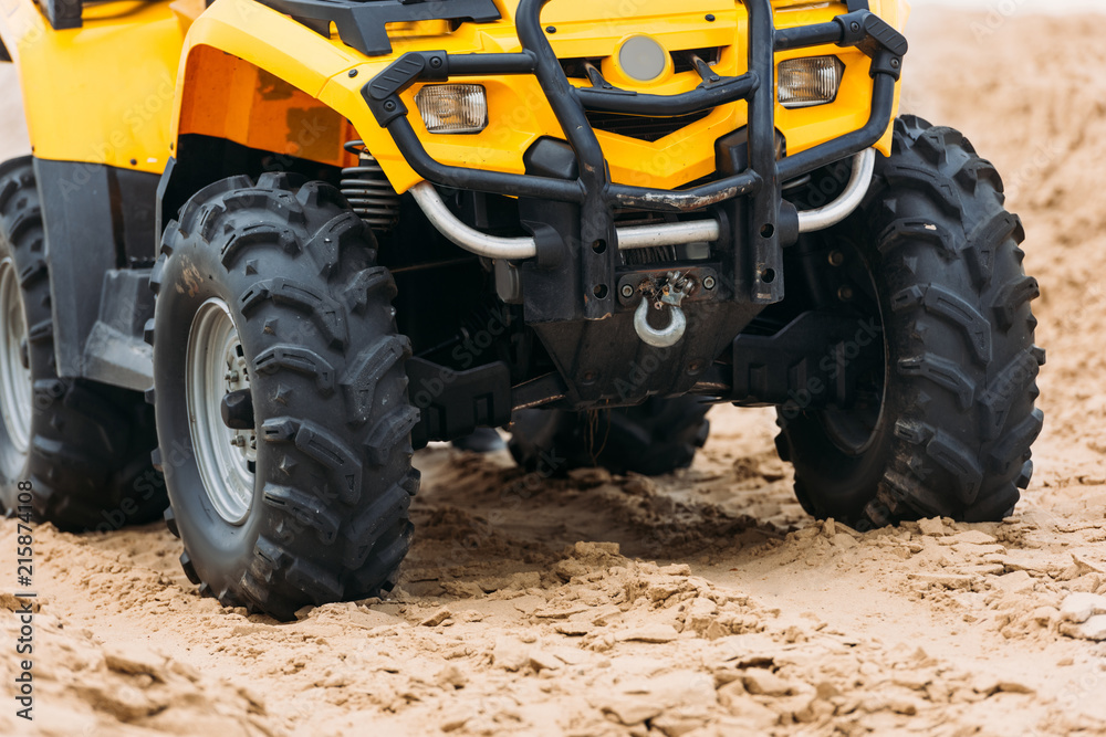 partial view of all-terrain vehicle on sand partial view of all-terrain vehicle on sand