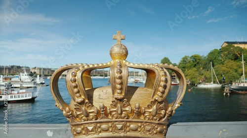 Royal Swedish crown on the Skeppsholmbron bridge over the river with harbor in the background. One of the sights of the city. Gamla Stan, Stockholm, Sweden photo