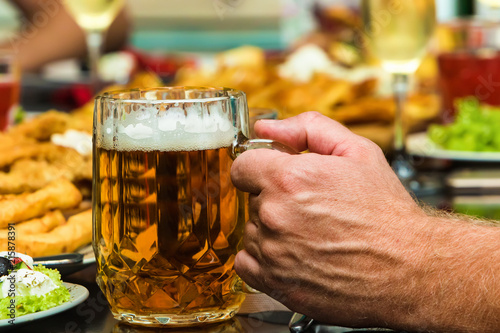 Hand with beer on the table with food