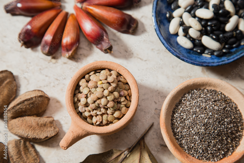 Composition with rustic pottery bowls of chia seeds, Lentils, and beans. Pinions and 'Castanha-do-Pará' nuts. Laurel Nobilis aromatic leafs Composition with rustic pottery bowls of chia seeds, Lentils, and beans. Pinions and 'Castanha-do-Pará' nuts. Laurel Nobilis aromatic leafs