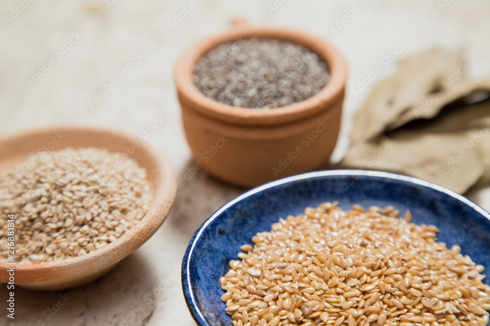 Composition with pottery bowls containing chia seeds, linum seeds, and sesame. Laurel Nobilis leafs. Marble surface. Composition with pottery bowls containing chia seeds, linum seeds, and sesame. Laurel Nobilis leafs. Marble surface.