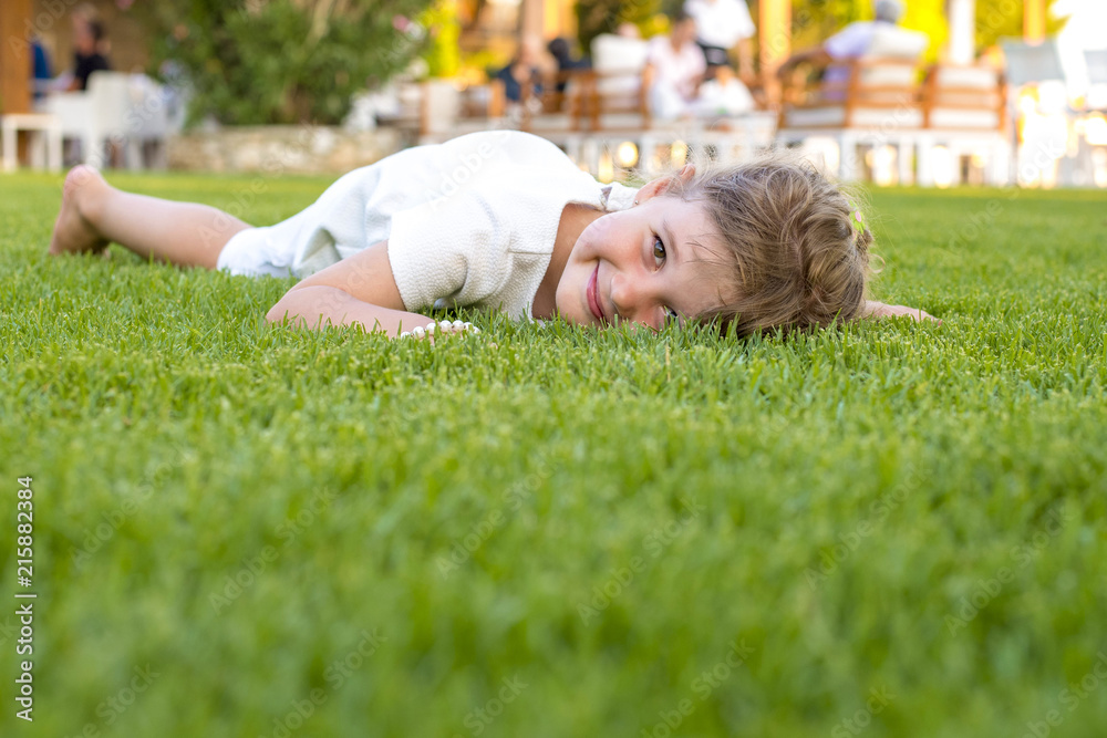 Adorable smiling girl laying in the grass on a summer day Adorable smiling girl laying in the grass on a summer day