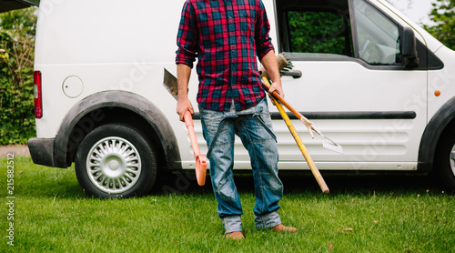 Anonymous male gardener with tools and van