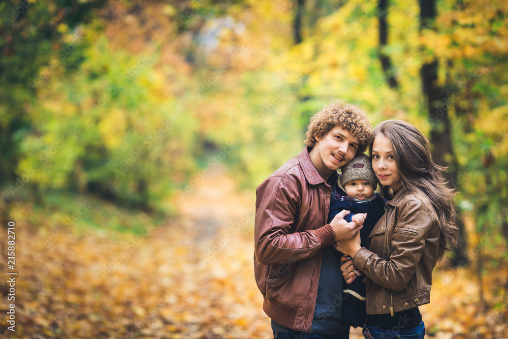 Fototapeta premium Young happy family hugging in autumn in park.