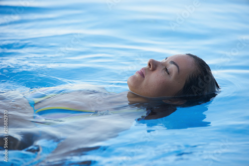 Beautiful Woman tourist in infinity pool of hotel resort enjoying the view over the ocean