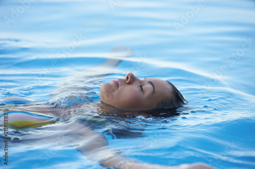 Young Woman tourist in infinity pool of hotel resort enjoying the view over the ocean