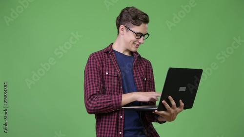 Young handsome teenage nerd boy using laptop