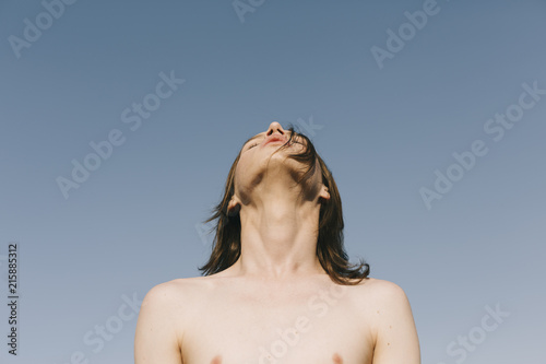 Young shirtless man standing outdoors photo