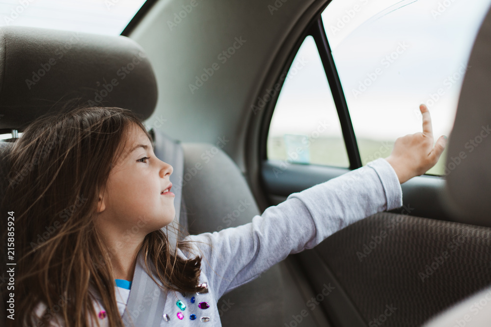 Girl looking out the window of car on a road trip Stock Photo | Adobe Stock